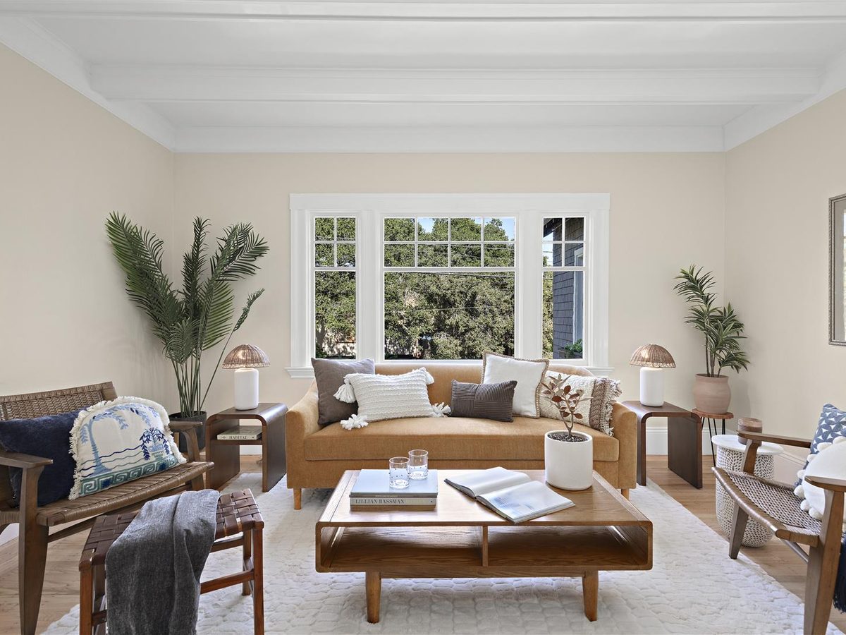 Bright living room with a white beamed ceiling, a bay of windows and warm wood furniture